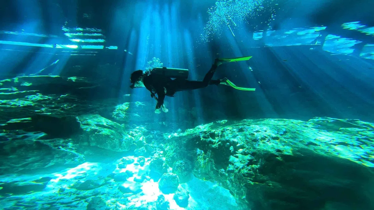 Diver following the guideline through Dos Ojos cavern on a two-tank cenote dive, Tulum Mexico