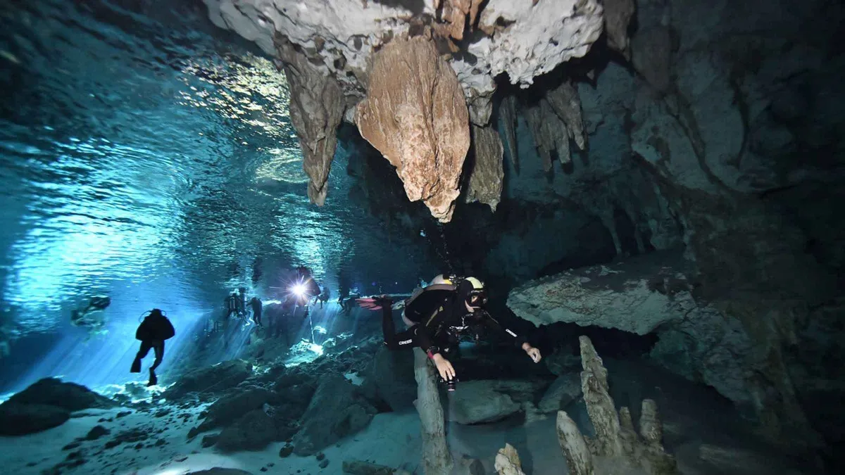 Diver in the light zone of a flooded cavern on a two-tank cenote dive, Tulum Mexico